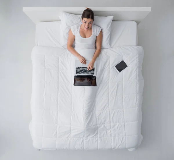 Mujer usando un portátil en la cama —  Fotos de Stock