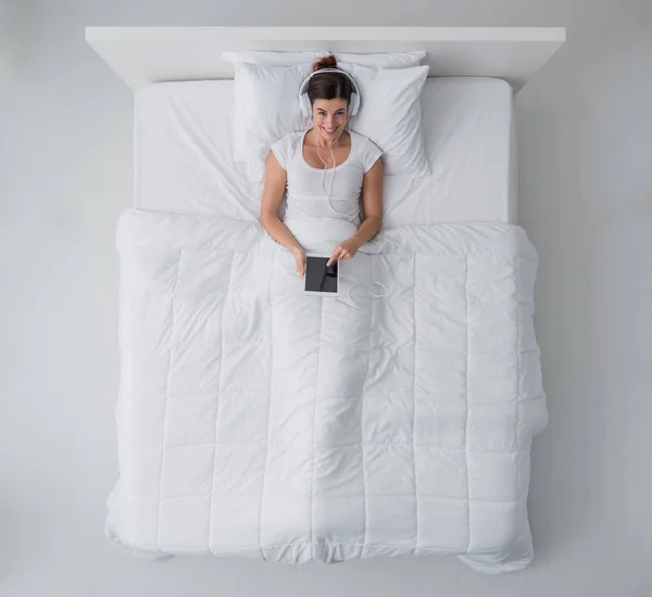 Mulher na cama conectando com um tablet — Fotografia de Stock