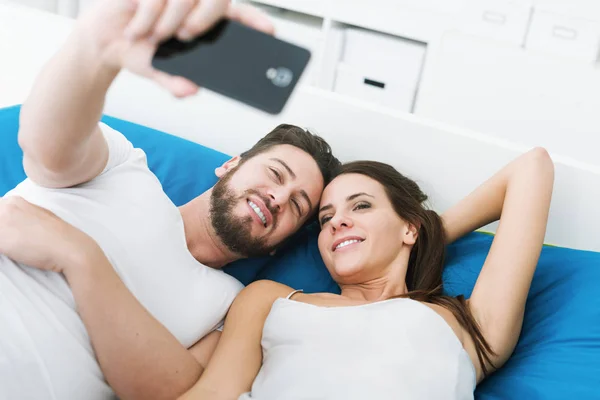 Pořizování selfie pár v posteli — Stock fotografie