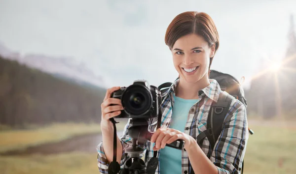 Усміхнена жінка ходить на відкритому повітрі і знімає зі своєю цифровою камерою, використовуючи триногу, концепцію фотографії природи — стокове фото