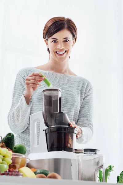 Mujer que usa un extractor de jugo y prepara una bebida desintoxicante saludable con apio y otras verduras —  Fotos de Stock