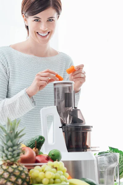 Mujer que usa un extractor de jugo y prepara una bebida desintoxicante saludable con apio y otras verduras — Foto de Stock