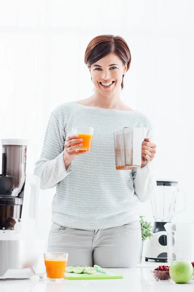 Mujer que usa un extractor de jugo y prepara una bebida desintoxicante saludable con apio y otras verduras — Foto de Stock