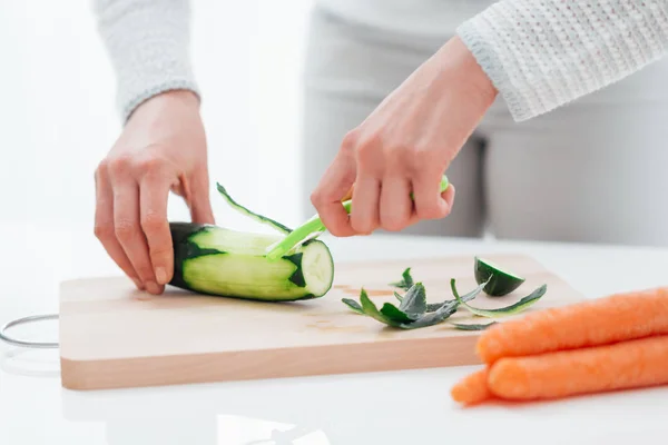 Woman peeling a cucumber — Stock Photo, Image