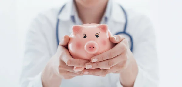 Female doctor and piggy bank: health insurance — Stock Photo, Image