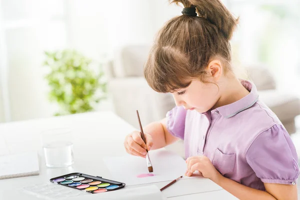 Милая девочка из детского сада рисует дома — стоковое фото