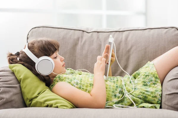 Sevimli kız kanepede rahatlatıcı ve tablet kullanma — Stok fotoğraf