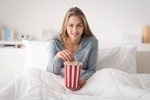 Счастливая женщина отдыхает в постели и смотрит фильмы по телевизору — стоковое фото