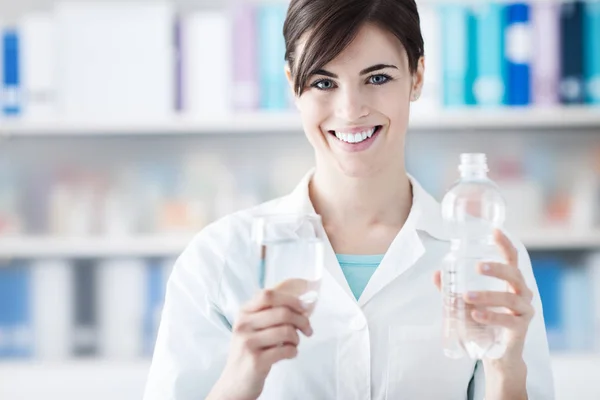 Доктор держит стакан воды и бутылку — стоковое фото