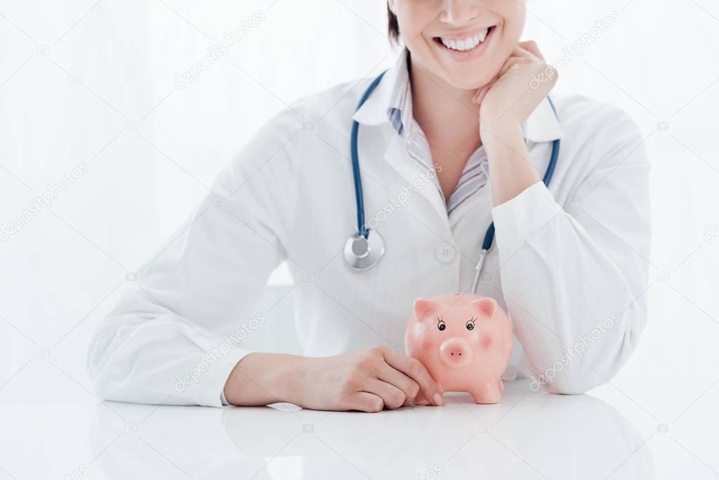 Female doctor and piggy bank: health insurance