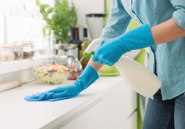 Kadın sprey deterjanla temizlik yapıyor.