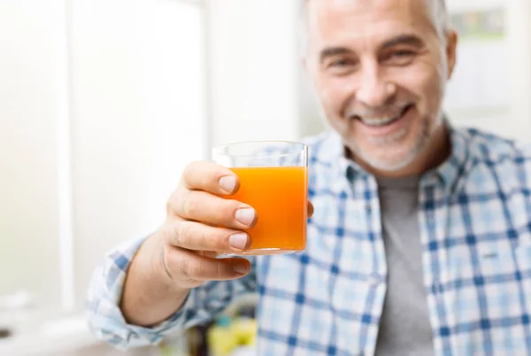 Улыбающийся человек выпивает стакан апельсинового сока — стоковое фото
