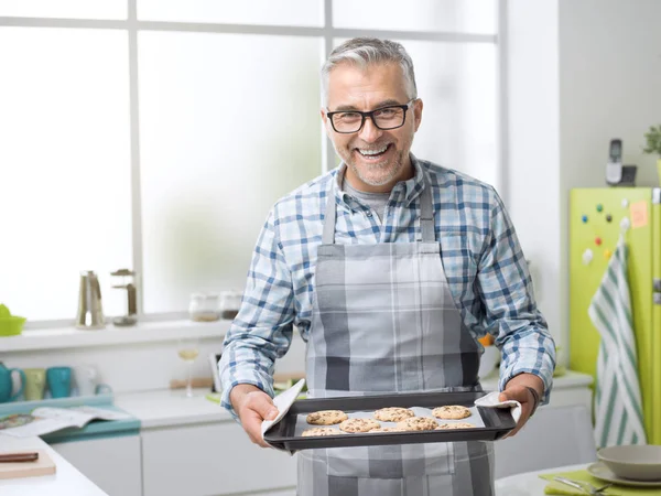 Hombre sonriente sosteniendo galletas recién horneadas —  Fotos de Stock