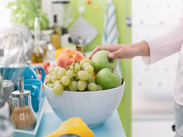 Mulher tomando uma maçã de uma tigela de frutas — Fotografia de Stock