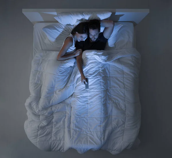 Sledování televize pár v posteli — Stock fotografie