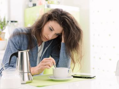 Tired woman having breakfast at home clipart