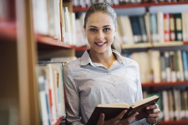 Žena vyhledávání knih v knihovně — Stock fotografie