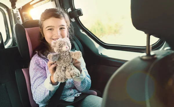 Vrolijk meisje in een auto met haar teddy bear — Stockfoto