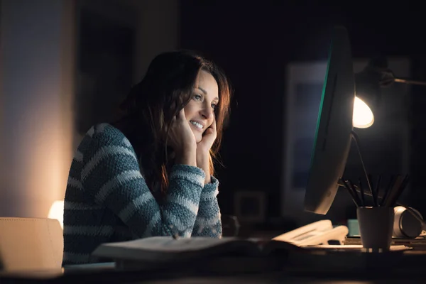 Щаслива жінка працює зі своїм комп'ютером вночі — стокове фото