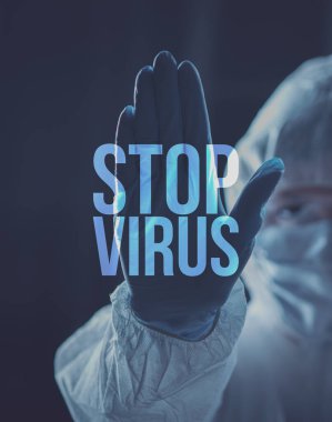 Doktor ve bilim adamı koruyucu giysi giyip, jest yaparak Coronavirüs konseptini durduruyorlar.