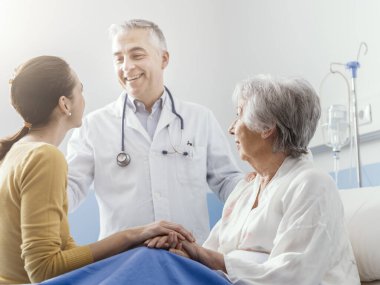 Profesyonel gülümseyen doktor, kıdemli bir hasta ve kızıyla hastanede buluşuyor.