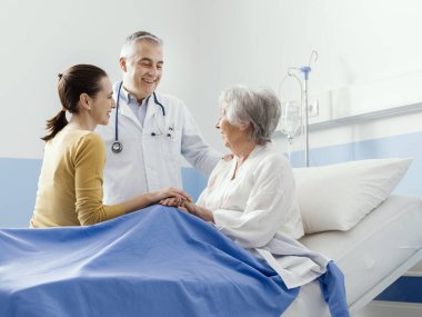 Profesyonel gülümseyen doktor, kıdemli bir hasta ve kızıyla hastanede buluşuyor.