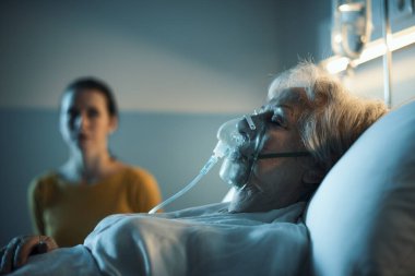 Geceleri yaşlı bir hastaya oksijen maskesi takan bir kadın, yaşlı bakım konsepti