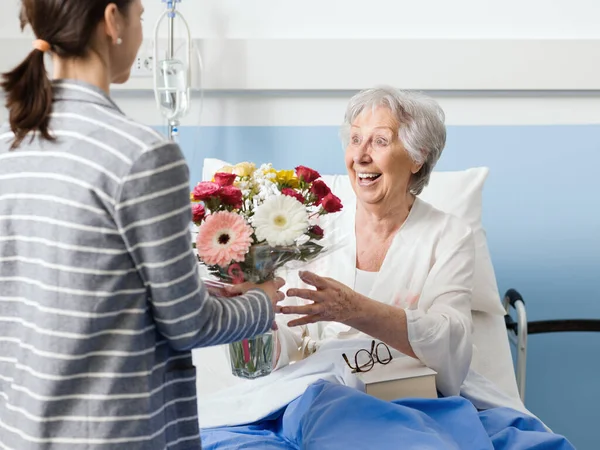 Young Woman Visiting Her Grandmother Hospital Giving Her Flowers — Stock Photo, Image