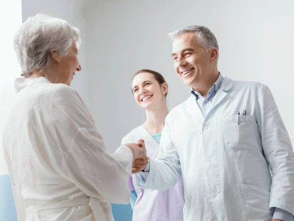 Gülümseyen Profesyonel Doktor Hemşire Klinikte Kıdemli Bir Hastayla Buluşuyor Sıkışıyorlar — Stok fotoğraf