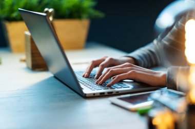 Profesyonel iş kadını masa başında oturuyor ve laptopuyla evden çalışıyor.