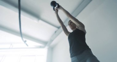 Spor salonunda kettlebell ile egzersiz yapan formda bir kadın. Güç antrenmanı ve fitness konsepti.