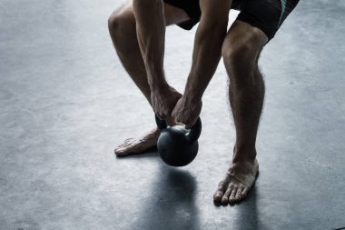 Spor salonunda egzersiz yapan atletik bir adam halter olarak ağırlık kaldırıyor.