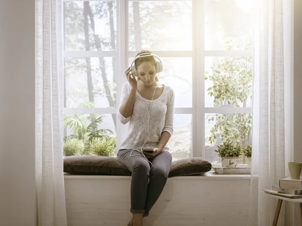 Розслаблена Щаслива Жінка Сидить Біля Вікна Вдома Слухає Музику Допомогою — стокове фото