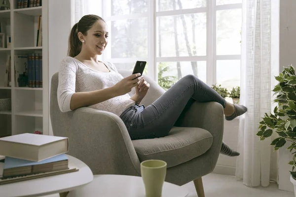 Chica Joven Feliz Usando Teléfono Inteligente Casa Ella Está Relajando — Foto de Stock