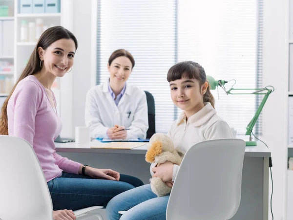 小児科医に会う医務室の若い母親と子供たちは机に座っています — ストック写真
