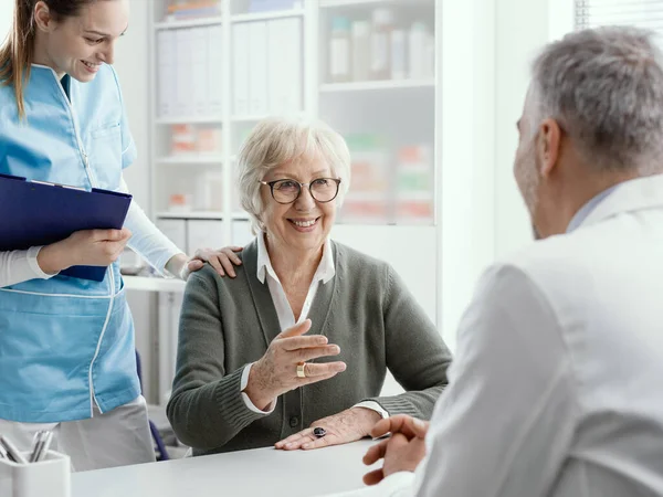 Sorrindo Mulher Idosa Conversando Com Médico Seu Escritório Uma Enfermeira — Fotografia de Stock