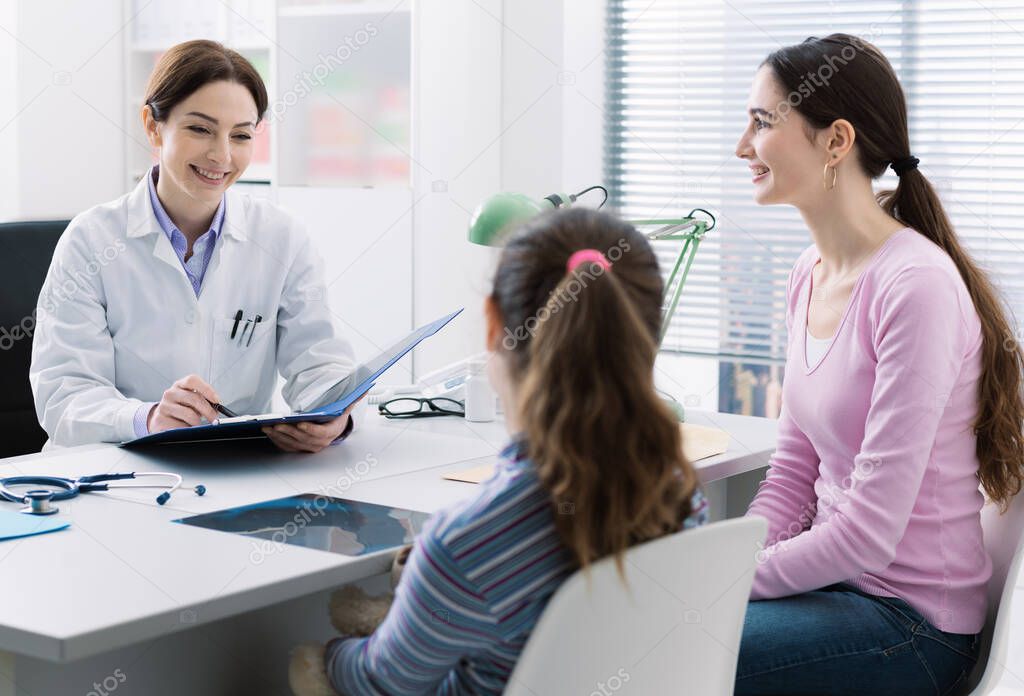 Young mother and child in the doctor office meeting the pediatrician, they are sitting at desk