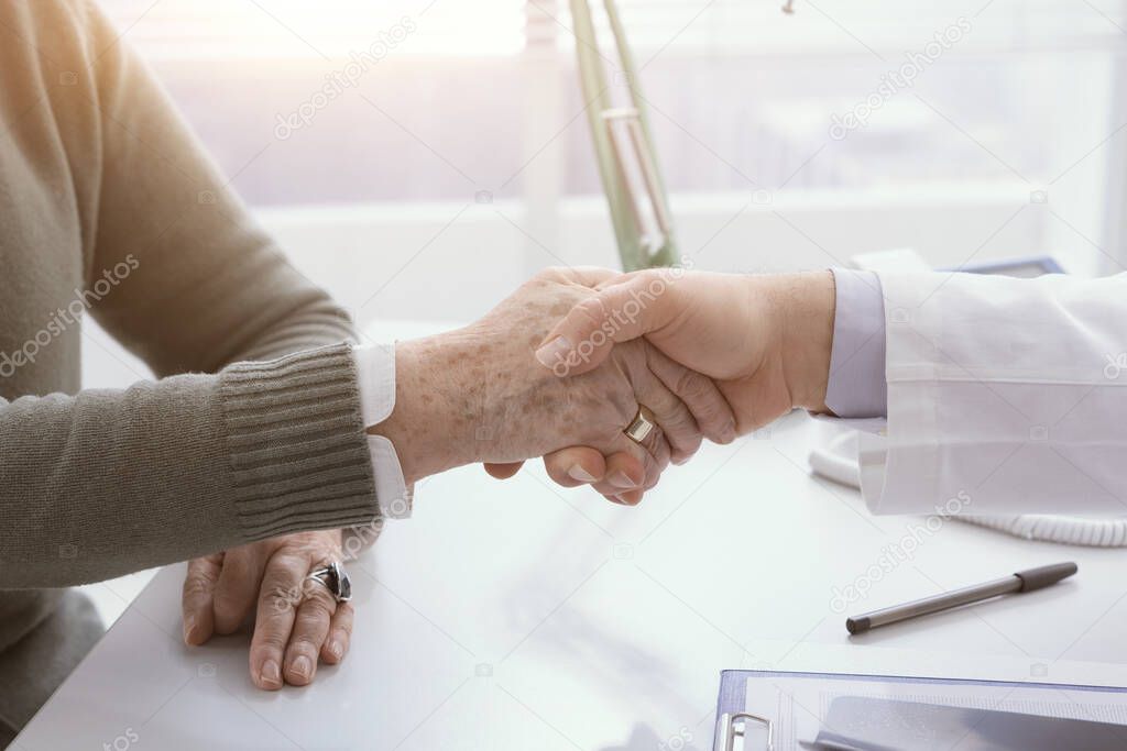 Doctor and senior patient shaking hands in the office before visiting, healthcare and assistance concept