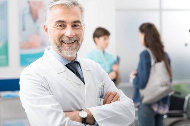 Bir doktor portre için poz verir ve kameraya gülümser.