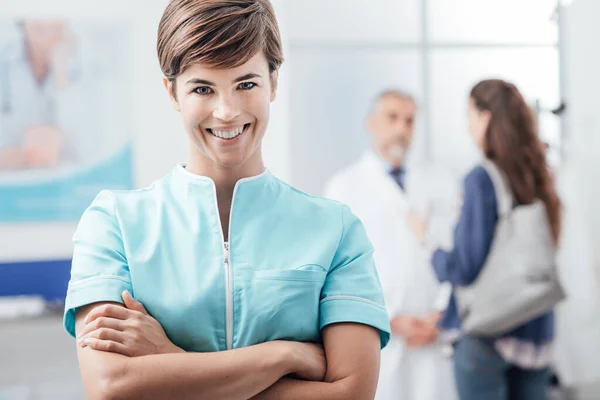 Sorrindo Jovem Enfermeira Posando Clínica Com Braços Cruzados Médico Está — Fotografia de Stock