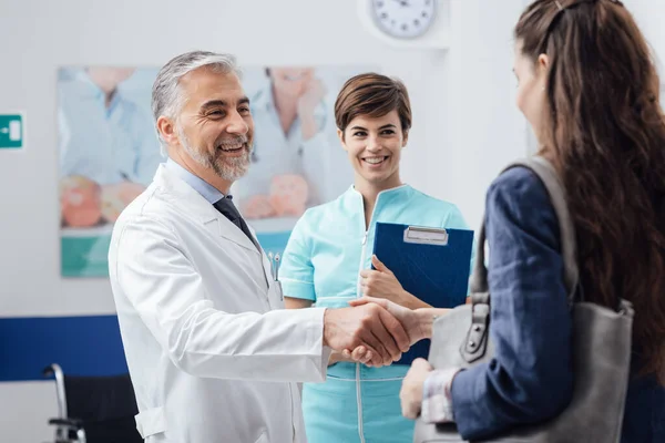 診療所で患者を歓迎する医療スタッフ 医師は握手と笑顔 医療サービスと医療専門家の概念を与えています — ストック写真