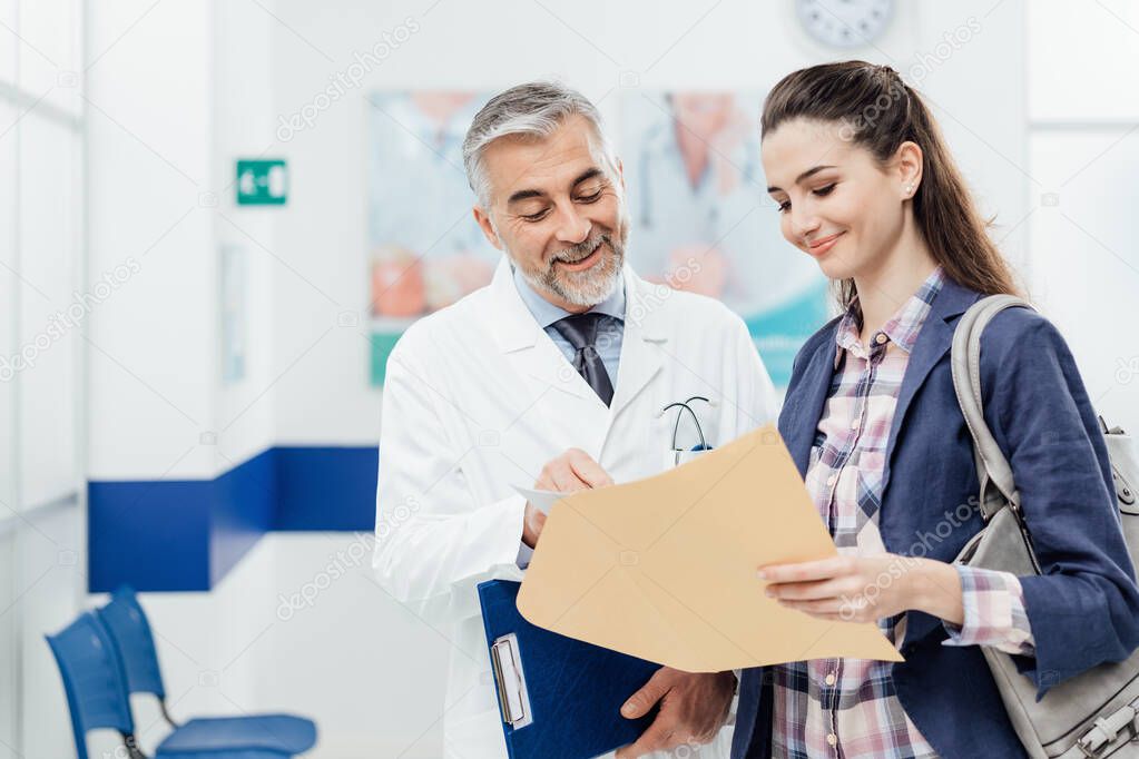 Smiling confident doctor explaining medical records to a young female patient