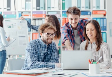 Genç iş adamları bir projeyi tartışıyor ve bir dizüstü bilgisayarla bağlantı kuruyor, başlat ve takım çalışması kavramını başlat