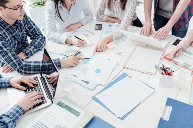 İş adamları ofiste toplanıyor ve mali stratejileri tartışıyorlar. Raporları ve evrakları kontrol ediyorlar. Tanınmayan insanlar.