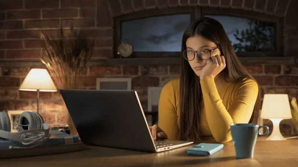 机に座ってノートパソコンと自宅で接続する若い美しい女性 彼女は彼女の仕事に焦点を当てています — ストック写真