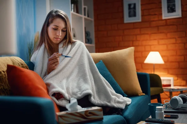 Sick Woman Sitting Sofa Home Measuring Her Temperature Thermometer She — Stock Photo, Image