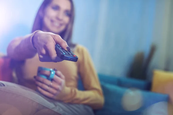 Sorrindo Mulher Sentada Sofá Casa Assistindo Televisão Ela Está Segurando — Fotografia de Stock