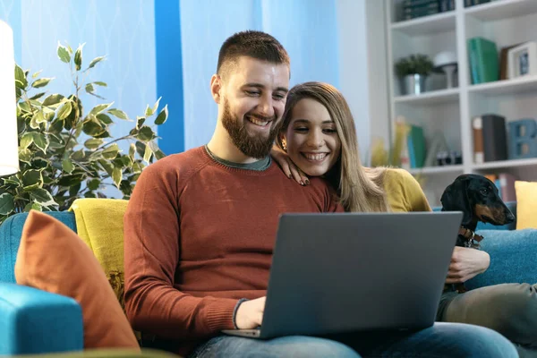 Feliz Pareja Joven Sentada Sofá Casa Con Perro Conectándose Línea — Foto de Stock