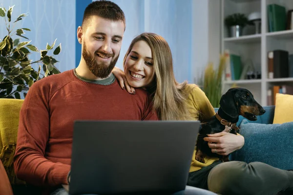 Feliz Pareja Joven Sentada Sofá Casa Con Perro Conectándose Línea — Foto de Stock