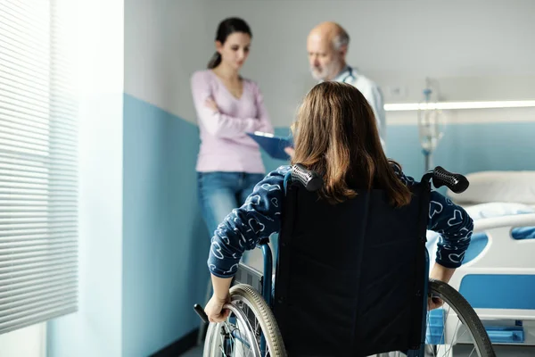 병원에서 휠체어를 어머니와 의사는 자신의 건강에 이야기하고 — 스톡 사진